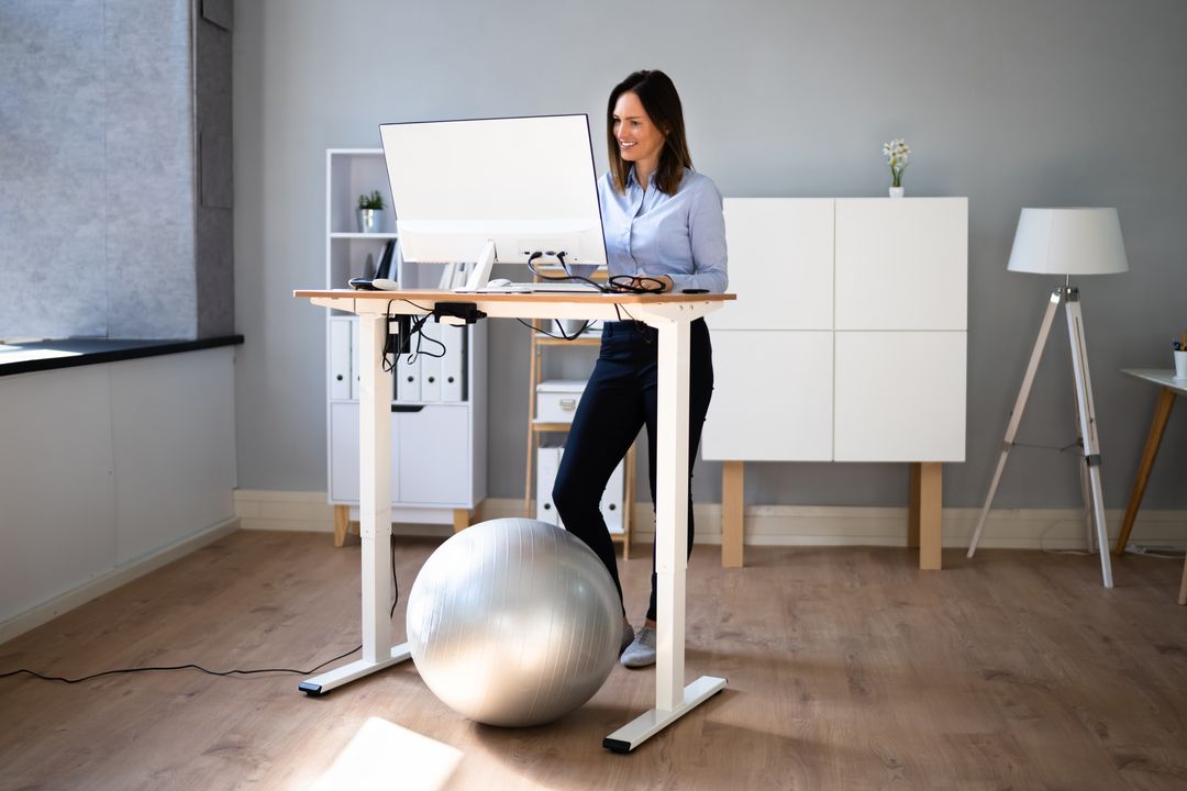 Frau verwendet höhenverstellbaren Schreibtisch für eine gute Haltung.