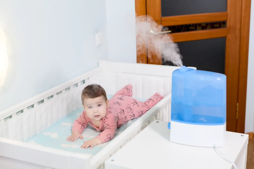 Ultraschall-Luftbefeuchter im Kinderzimmer neben einem Babybett